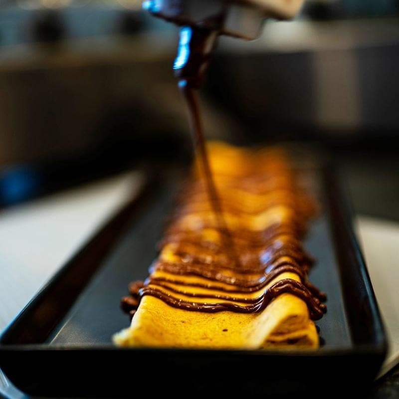 A pistachio crepe with strawberries on black slate