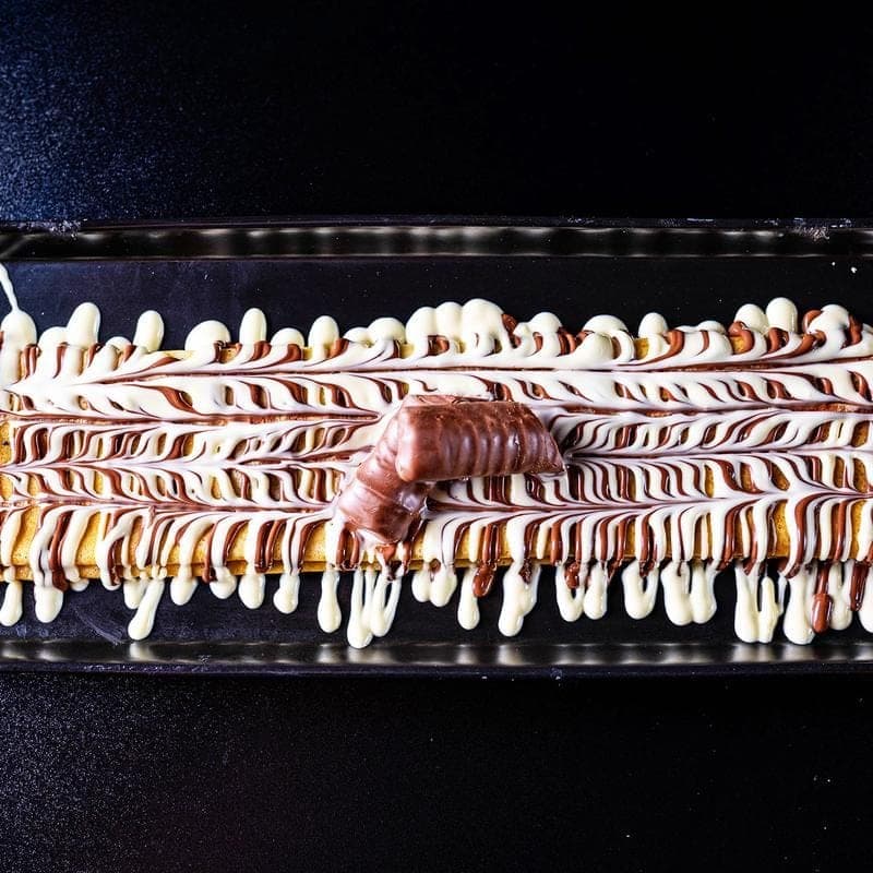 A crepe striped with Nutella and white chocolate on a black slate board
